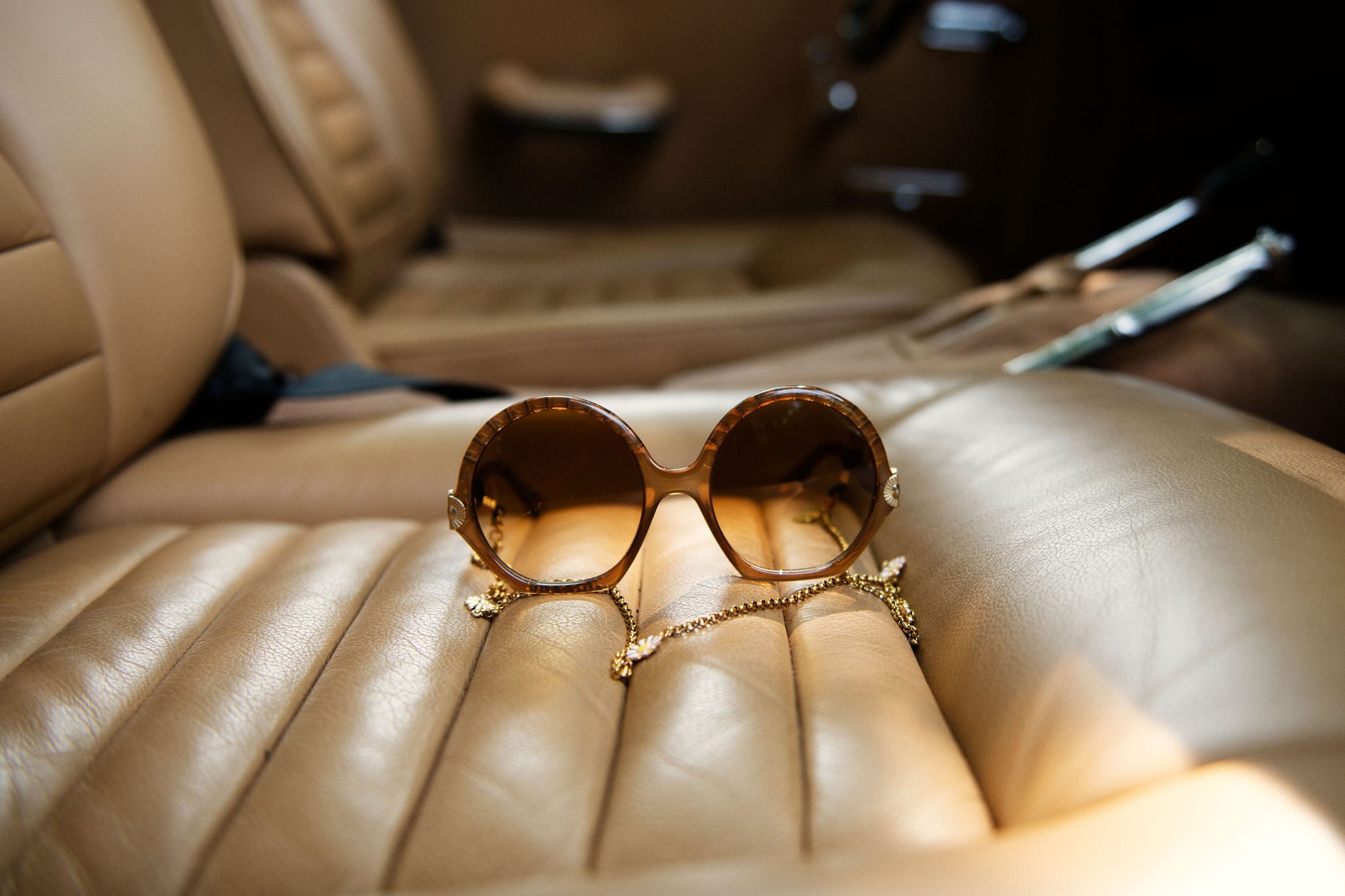 lunettes de soleil avec chainette doré posé sur siège avant d'une vieille voiture